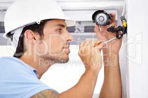 Your home security is in capable hands. Shot of a handsome young man installing a security camera.