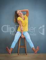 Positivity is contagious, pass it on. Shot of a young woman sitting on a chair against a gray wall.