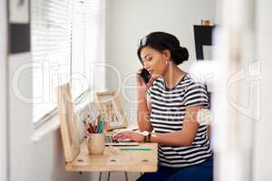 I turned my talent into a successful business. Shot of an attractive young artist using a laptop and making a phone call inside her studio at hom.
