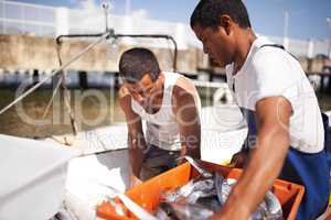 Its hard work to be a fisherman. Cropped shot of two fishermen on their boat with the fish they caught.