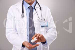 This is the recommend dose. Cropped shot of a doctor emptying a bottle of pills into his hand.