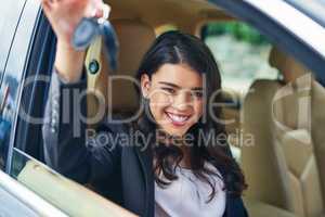 The keys to freedom and accessibility. Shot of an attractive young woman excited about her new car.
