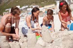 Dreams made of sand and sun. Shot of a happy family building sandcastles together at the beach.