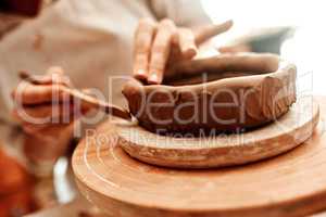 Its fun and rewarding to turn a piece of clay into art. Cropped shot of a woman shaping a clay pot in her workshop.