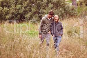 Marriage can be a walk in the park. A young couple laughing as the walk in a field.