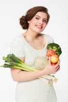 Healthy on the inside, happy on the outside. Pretty brunette woman holding healthy veggies while isolated on white.