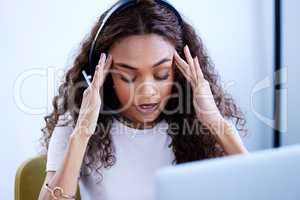 Its been an overwhelming day. Shot of a young call centre agent looking stressed out while working in an office.