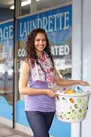 Off to do the laundry. Portrait of a young attractive woman carrying her laundry to the laundromat.