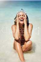 Its always fun in the sun. Cropped shot of an attractive young woman in scuba gear laughing while sitting on the beach.