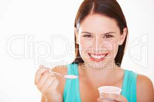 Yoghurt is both healthy and tasty. Portrait of a beautiful young woman eating a yoghurt.