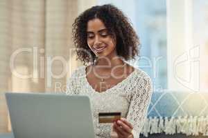 Making my monthly payments the easy way. Shot of an attractive young woman making payments online with a credit card at home.