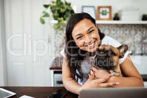 The road to my heart is filled with paw prints. Portrait of a young woman sitting with her pet dog on her lap while working from home.
