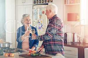 Heres to our perfect lifetime together. Shot of a smiling senior couple cooking together in their kitchen at home.