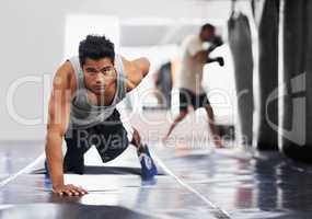 Pure fierce strength. Portrait of a focused young boxer doing push-ups in the gym.
