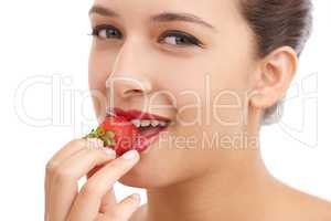 Luscious red lips. Cropped portrait of a beautiful young woman biting into a strawberry.