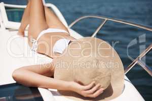 Living the high life. An attractive young woman tanning on the deck of a luxury yacht.