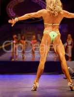 Braun and beauty. Rearview of a female bodybuilding contestant flexing for the judges.