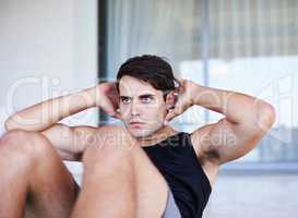 His fitness goals are always in sight. A cropped shot of a focused young man doing sit ups at home.