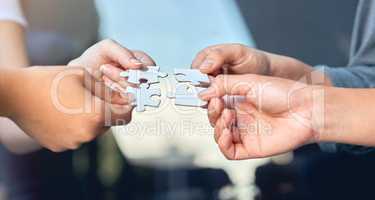Lets put it all together. Closeup of businesspeople about to put four puzzle pieces together.