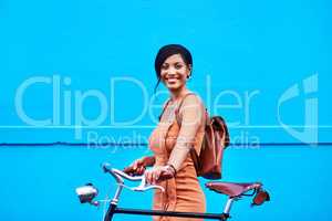 En route to happiness. Portrait of an attractive young woman traveling with her bicycle against a blue background.