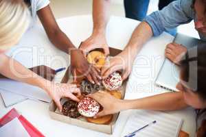 Energy for busy professionals. High angle shot of a group of businesspeople grabbing doughnuts while in a meeting.