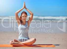 The divine in me honors the divine in you. Shot of a young woman practicing her yoga routine at the beach.