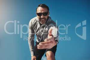 Come join me. Low angled portrait of a middle aged man standing on a rock and reaching out his hand.