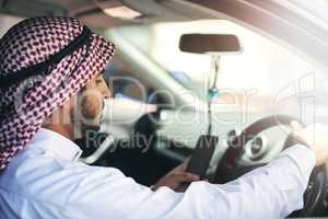 You have reached your destination. Shot of a young muslim businessman using his phone while driving a car.