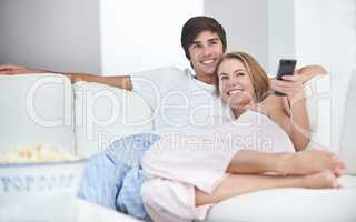 Ready for movie night. A young couple watching a movie at home.