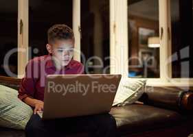 Too much tech too late. Shot of a young boy using a laptop past his bedtime at home.