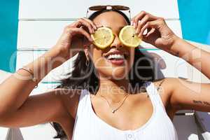 Life is all about the sweet and the sour. Cropped shot of a young woman posing with lemon slices over her eyes by the poolside.