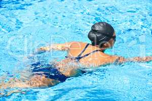 Taking her swimming seriously. Female swimmer making her way through a swimming pool stroke by stroke.