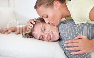 What a pleasant way to wake up. Shot of a woman leaning over and kissing her boyfriend lying on a sofa.