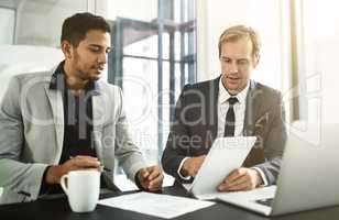Technology allows them to reach new economic markets. Shot of two businesspeople having a discussion in an office.