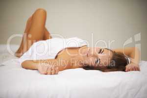 Beauty sleep. Full length shot of a beautiful woman lying on her back in bed covered only in her sheet.