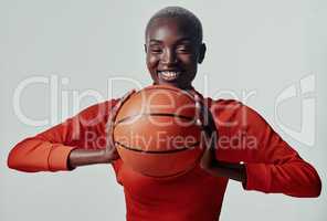 Keen for a couple of hoops. Studio shot of an attractive young woman playing basketball against a grey background.