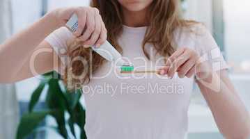 Dont forget to brush your teeth twice a day. Shot of a young woman applying toothpaste to a toothbrush.