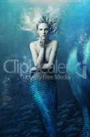 Shot of a mermaid swimming in solitude in the deep blue sea - ALL design on this image is created from scratch by Yuri Arcurs team of professionals for this particular photo shoot