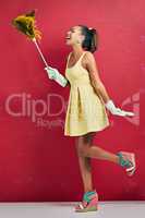 Dust the chores away. Studio shot of a young woman holding a feather duster against a red background.
