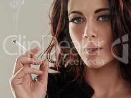 Shes a bad girl by nature. Portrait of an attractive young woman smoking a cigarette.