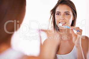 Keeping her teeth bright and white. A gorgeous young brunette brushing her teeth in the morning.