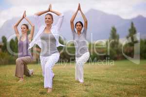 Follow me. A beautiful mature woman leading two young women in a yoga sequence.