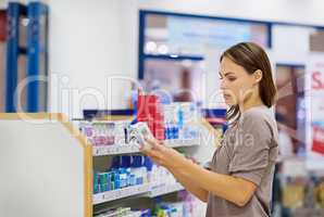 A young woman buying medicine in a pharmacy -The commercial designs displayed in this image represent a simulation of a real product and have been changed or altered enough by our team of retouching and design specialists so that they are free of any copy