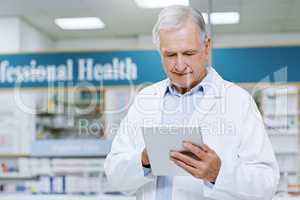 Always making sure were stocked on everything you need. Shot of a senior male pharmacist doing some work on his digital tablet.