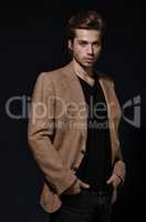 Model of style and poise. A handsome young model wearing a smart jacket posing against a black background.