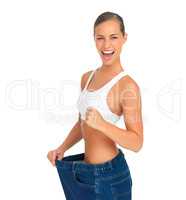 Ive dropped like 3 jeans sizes. Portrait of a sporty young woman looking excited pulling her pants away from her body.