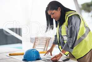 Making some minor adjustments. Cropped shot of an attractive young female construction worker looking over plans on site.