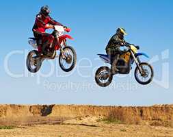 Jumping in unison. Action shot of two dirt bikers mid-air.