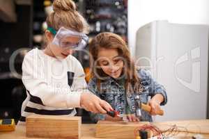 Playing with dads tools is the best. Shot of two little girls busy at work on creating something with tools.