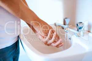 Stay safe from germs by washing your hands regularly. Closeup shot of an unrecognizable man washing his hands at a basin.
